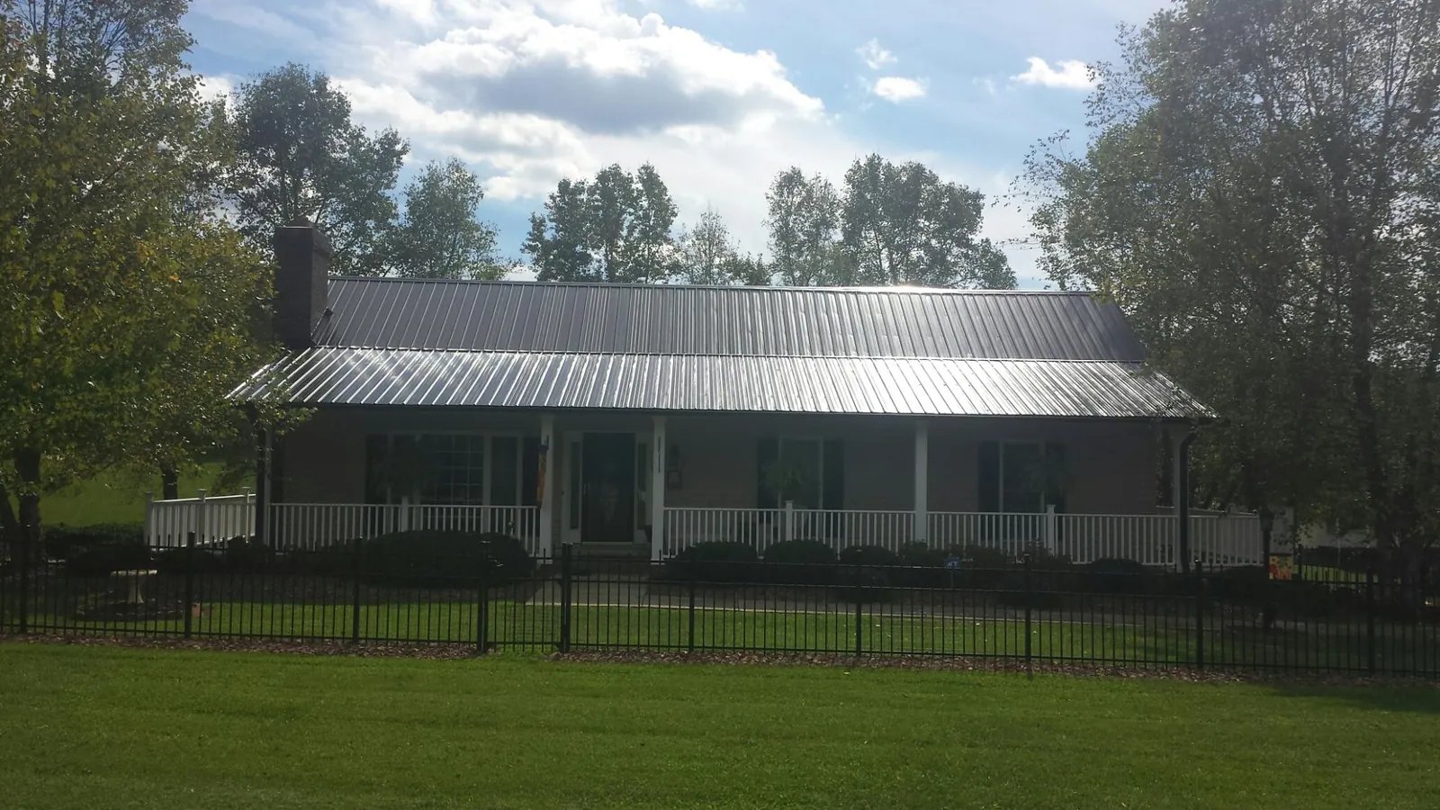 Gray metal roof on a brick ranch with a full width front porch — Gutter Guard Installation work by our crew in Wilkes Barre