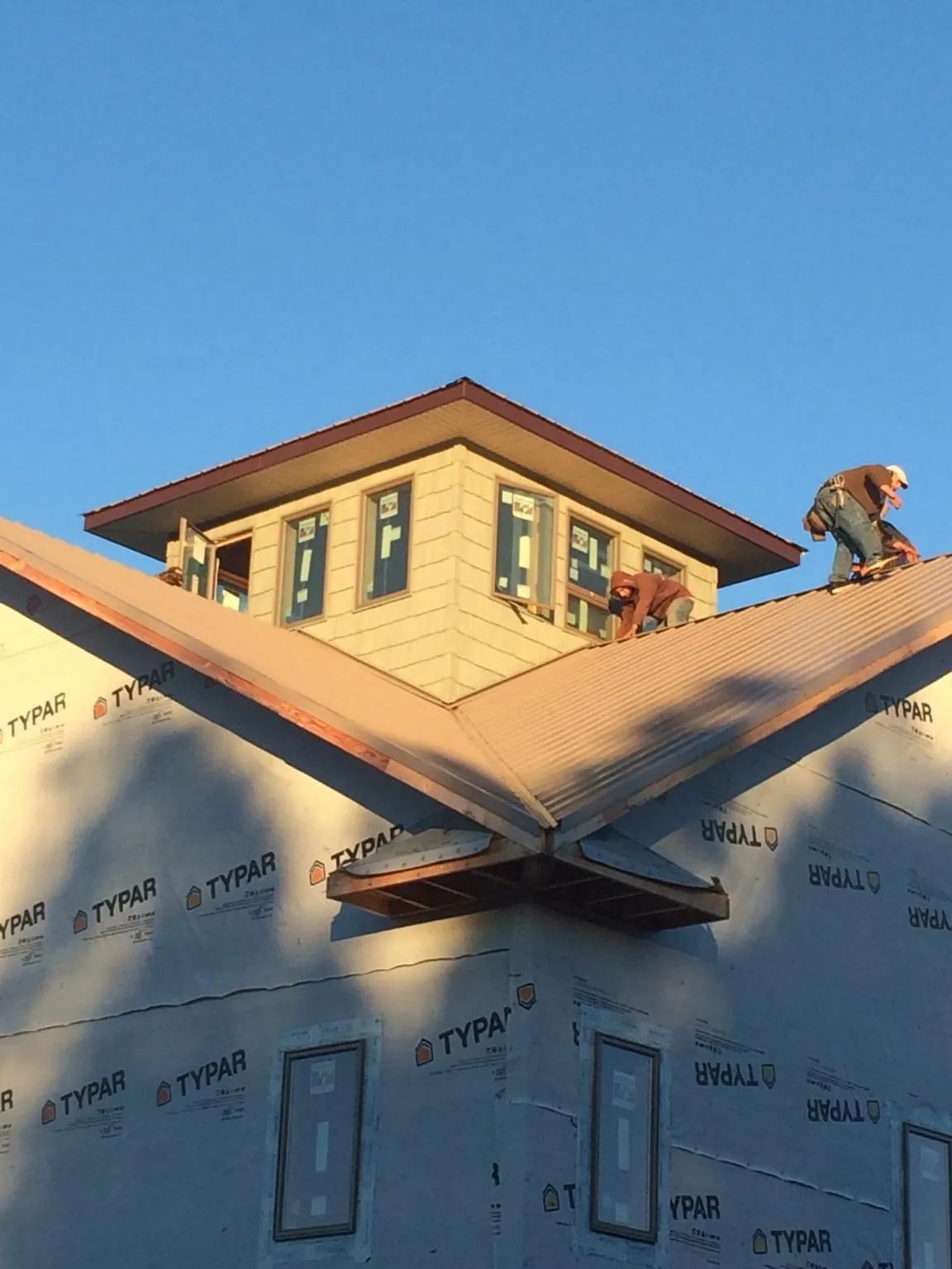 Roofers working around a rooftop cupola on a new metal roof at sunset — Roof Waterproofing in Wilkes Barre by Roofing Brothers